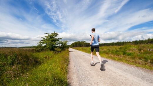 man running on road near grass field